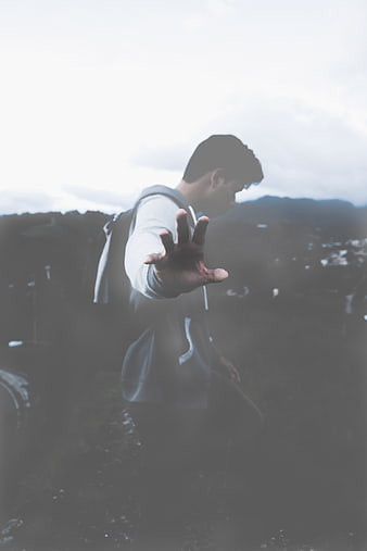 Man Reaching Hand Out in Misty Mountain Landscape