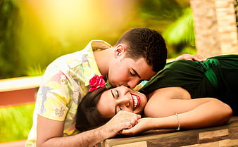 Happy couple kissing and laughing outdoors in tropical setting