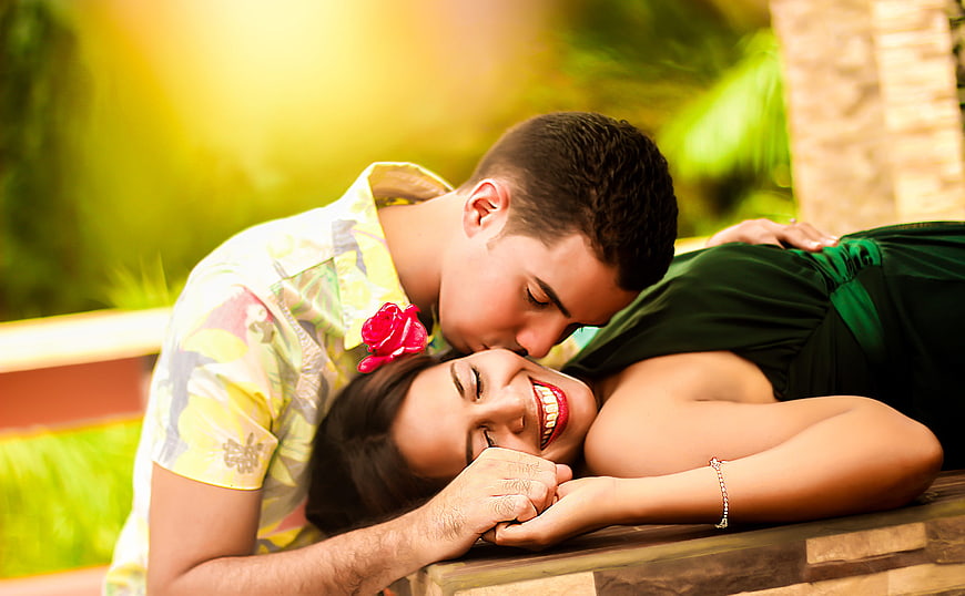 Happy couple kissing and laughing outdoors in tropical setting