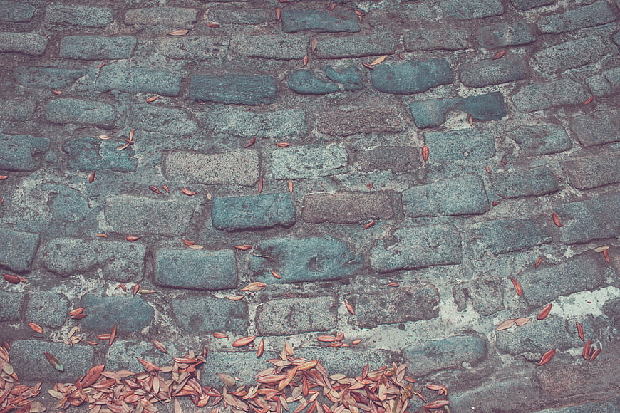 Textured Cobblestone Wall with Scattered Autumn Leaves