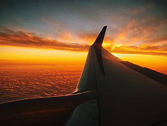 Airplane Wing Silhouette Against Vibrant Orange Sunset Sky
