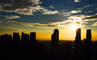 City Skyline Silhouette at Golden Sunset with Dramatic Clouds