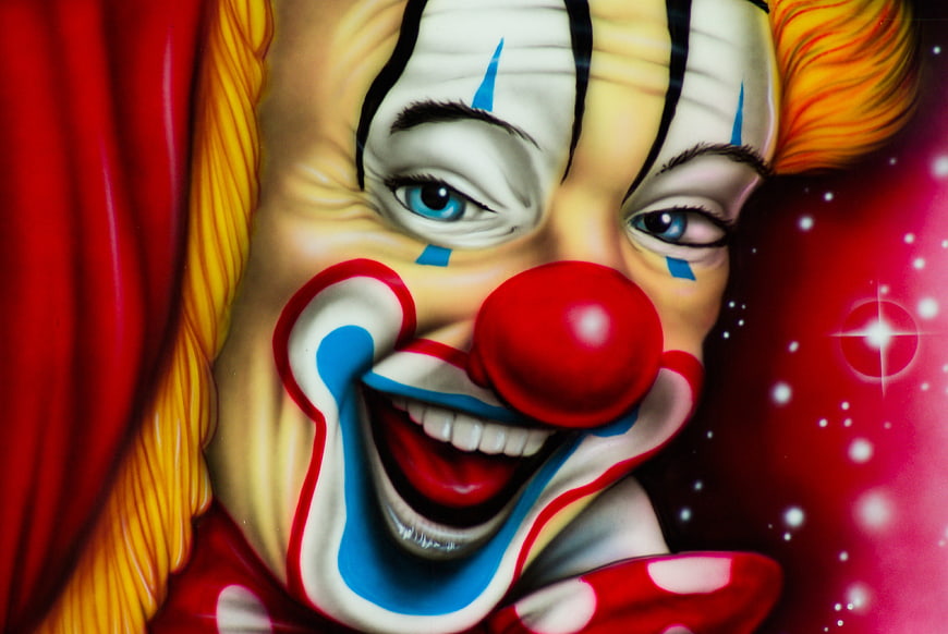 Close-up painting of a smiling clown face with red nose