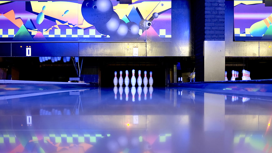 Neon bowling alley lane with pins and colorful mural