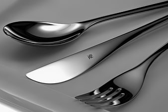 Close-up of polished silver cutlery including spoon, knife, and fork