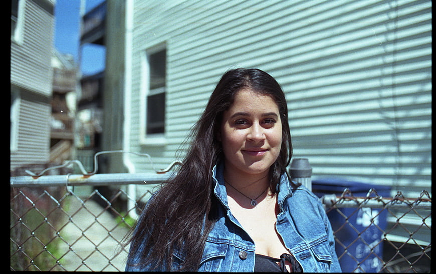Young woman in denim jacket smiling outdoors urban setting