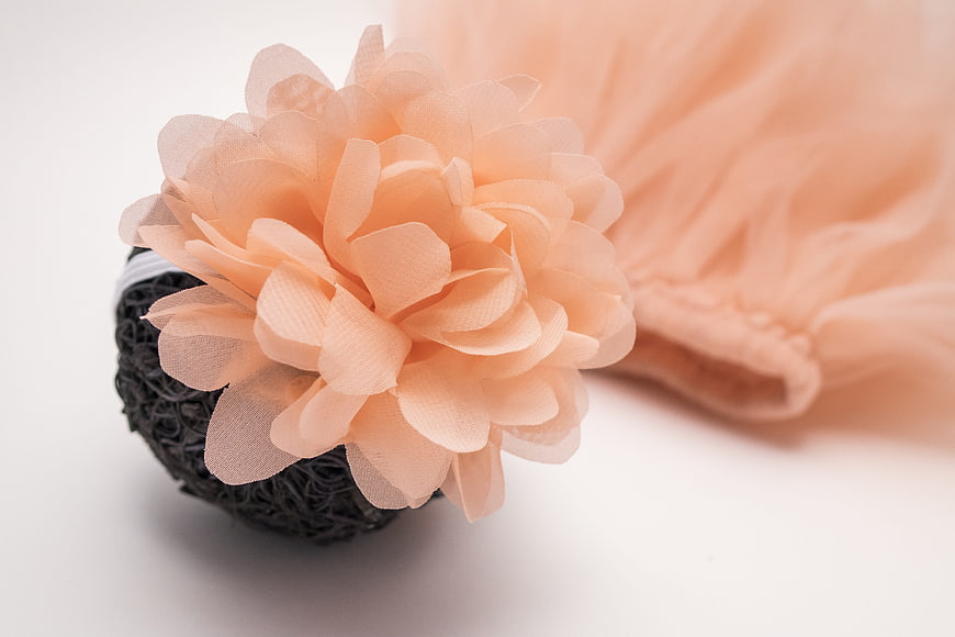 Peach fabric flower on black mesh base with tulle background