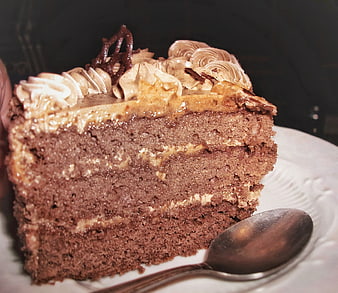 Slice of layered chocolate cake with caramel frosting and spoon