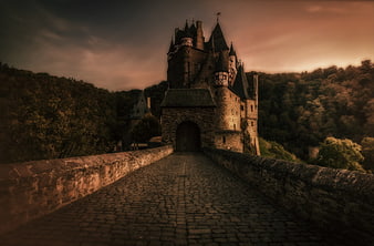 Medieval Castle Fortress At Dusk With Cobblestone Bridge