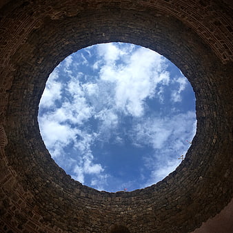 Low angle view of blue sky through ancient stone arch