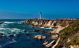 White Lighthouse on Rocky Coastal Cliff with Blue Ocean