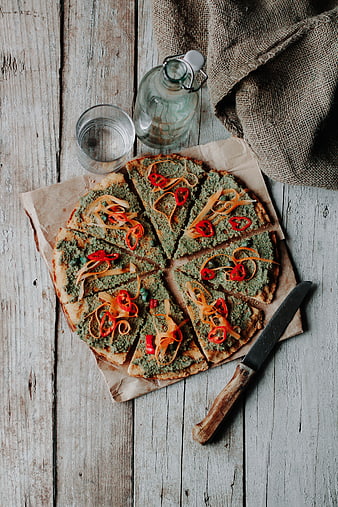 Top view of vegan green pizza on rustic wooden table