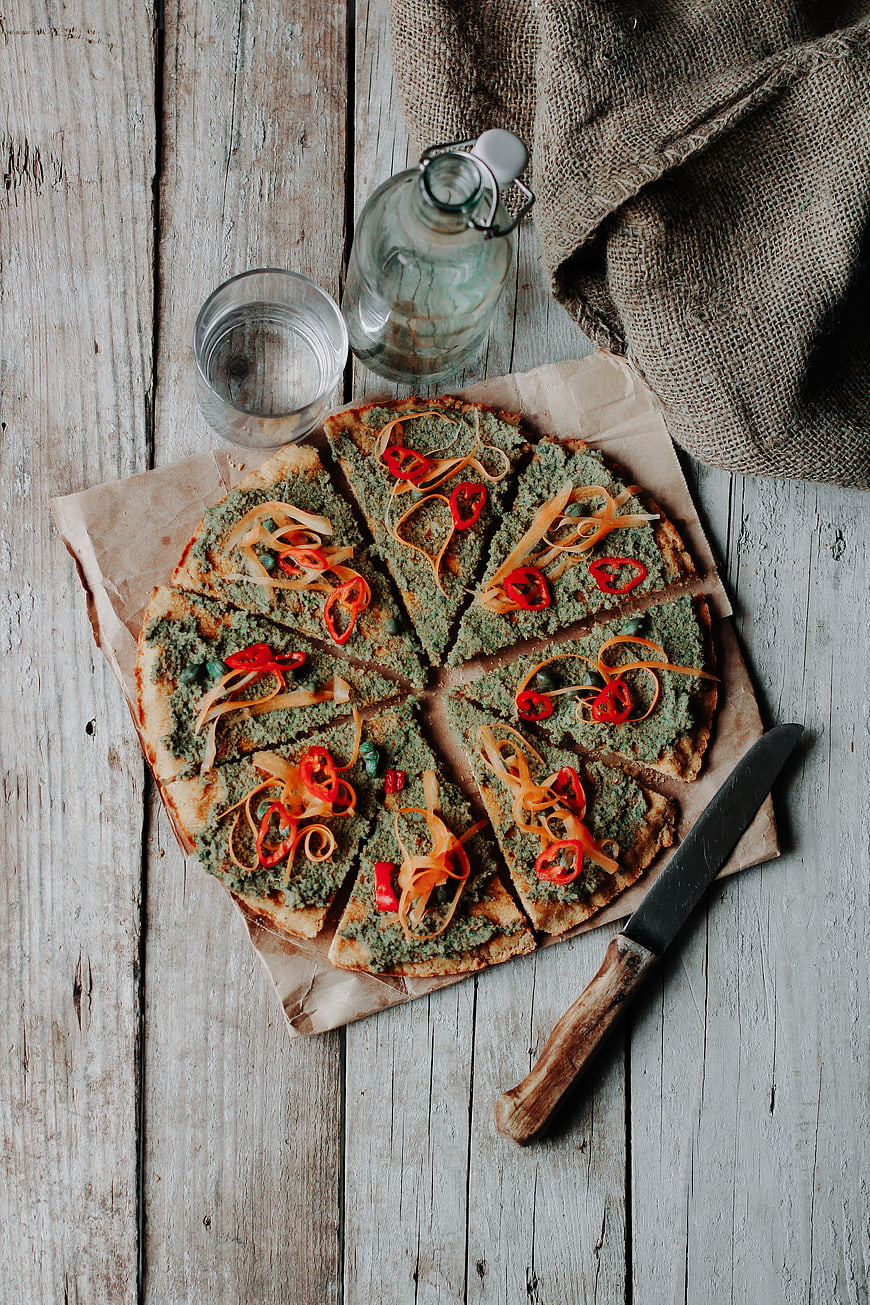 Top view of vegan green pizza on rustic wooden table