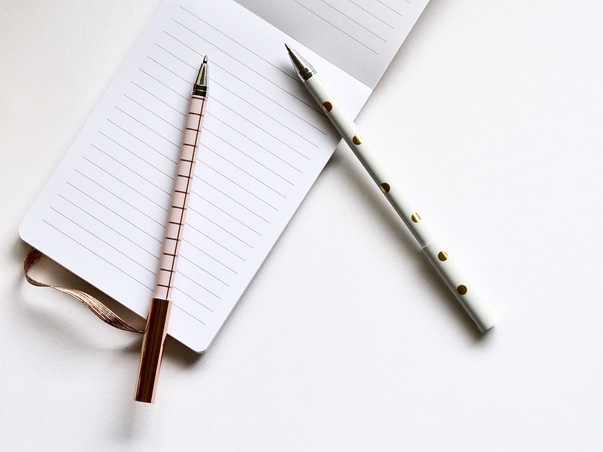 Minimalist white notebook and gold pens on white background