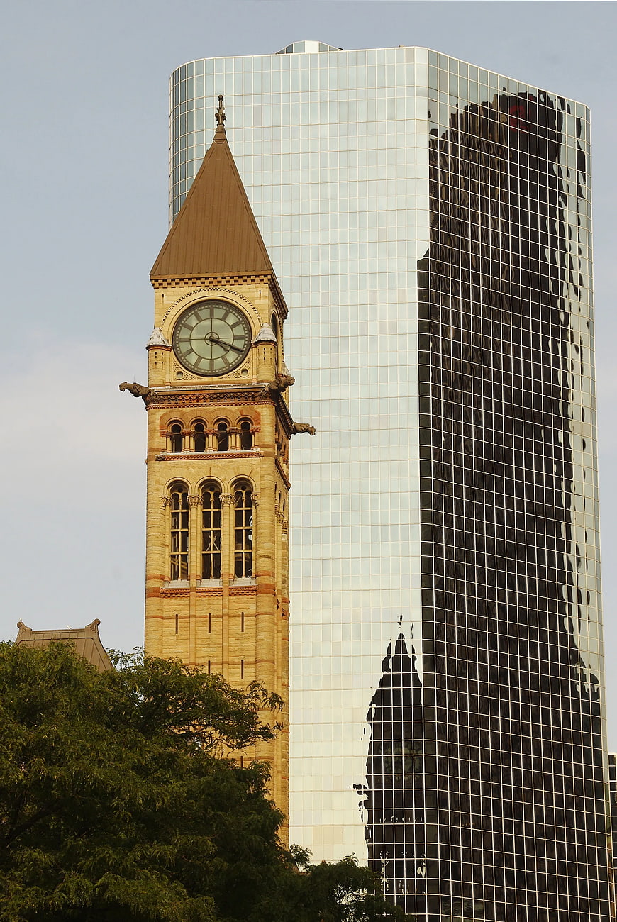 Historic Clock Tower Reflected in Modern Glass Skyscraper
