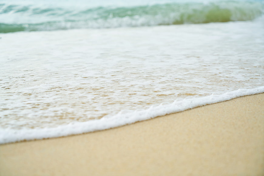 Close-up of gentle ocean waves washing over sandy beach