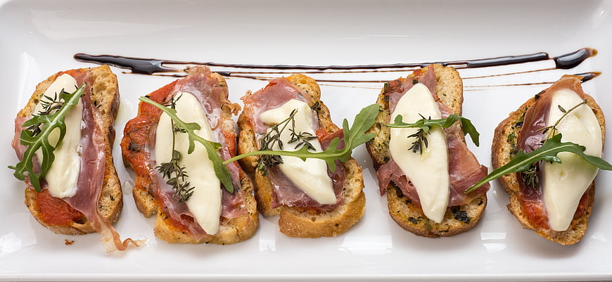 Gourmet Bruschetta Appetizer With Prosciutto, Mozzarella, And Arugula