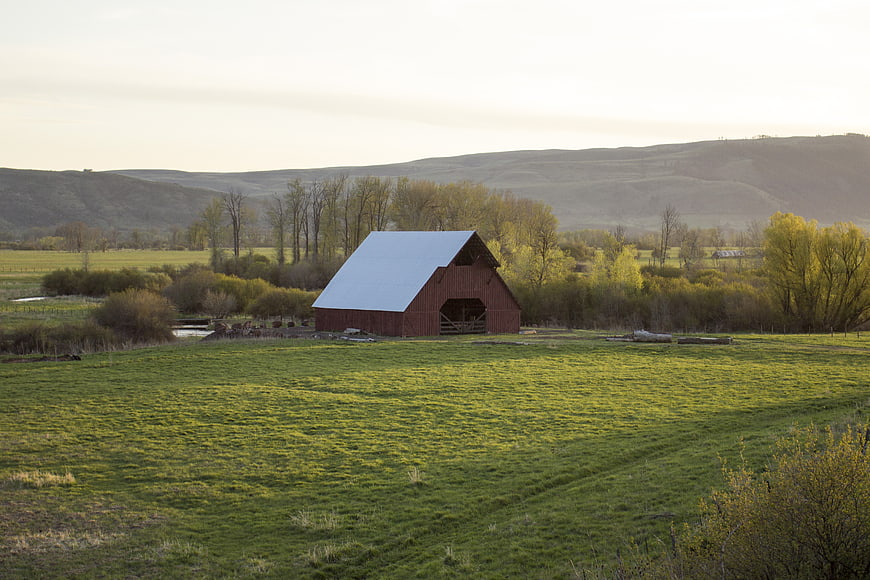 Red Barn in Green Pasture with Rolling Hills Background