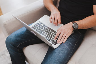 Man Typing on Laptop While Sitting on Couch