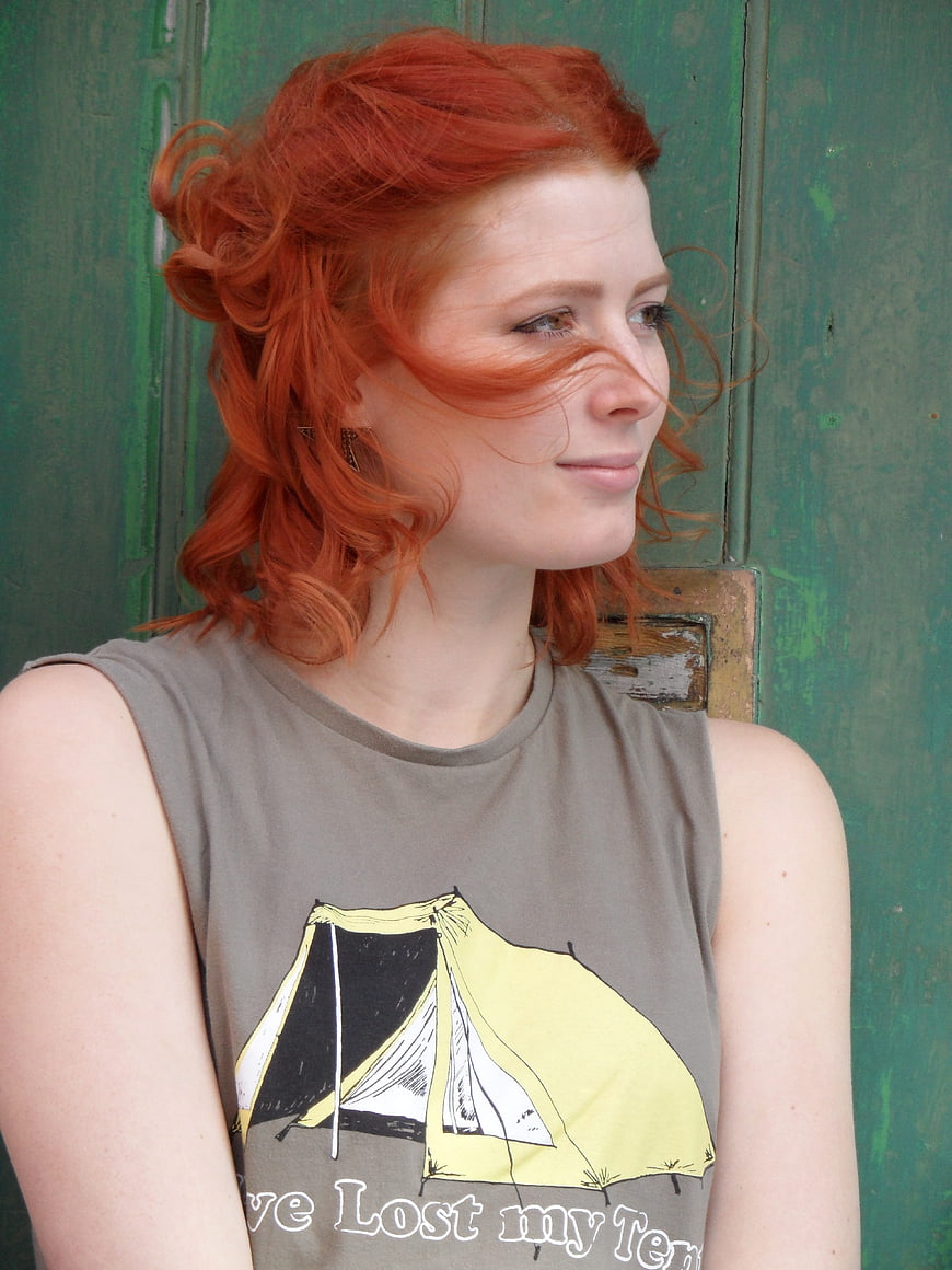 Portrait of woman with red hair against green wooden background