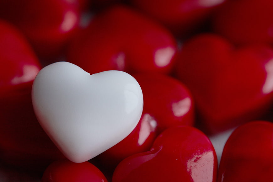 White Heart Candy Among Red Hearts Close Up