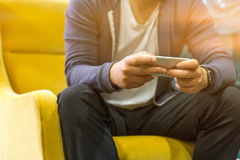 Man Using Smartphone on Yellow Chair