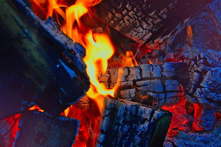 Close-up of burning wood logs with bright orange flames and glowing embers