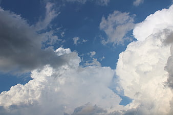 Dramatic white cumulus clouds against a deep blue sky