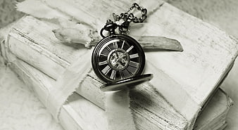 Vintage pocket watch on stack of old white books