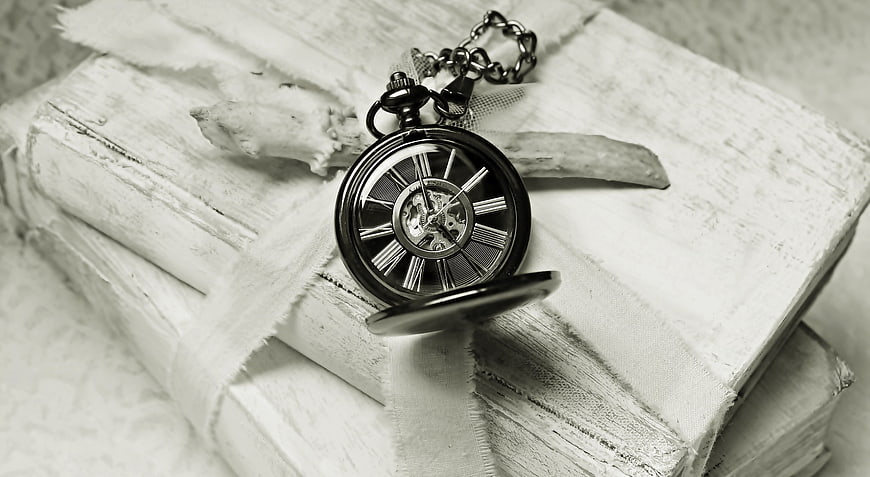 Vintage pocket watch on stack of old white books