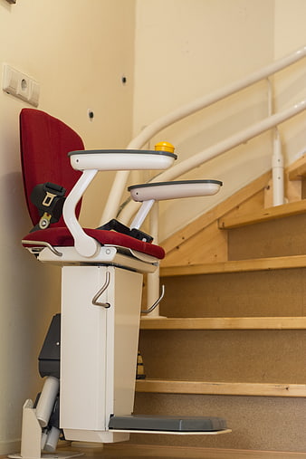 Red Stairlift Chair Installed On Wooden Staircase