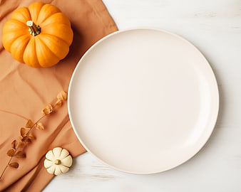Autumn flat lay with empty plate and pumpkins on white table