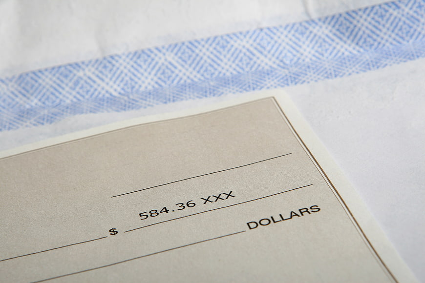 Close-up of a check with amount 584.36 on white envelope