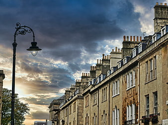 Historic stone townhouses under dramatic cloudy sky
