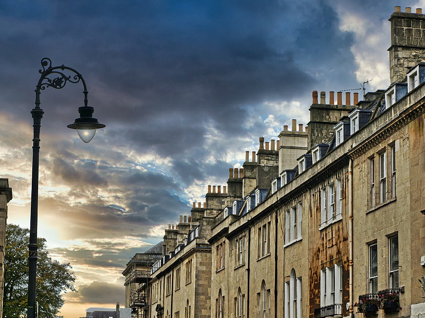 Historic stone townhouses under dramatic cloudy sky