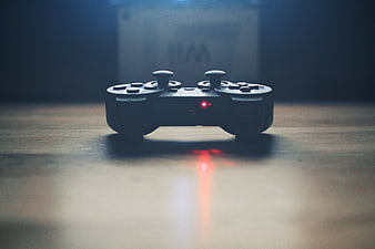 Dark moody gaming controller with red light on wooden table