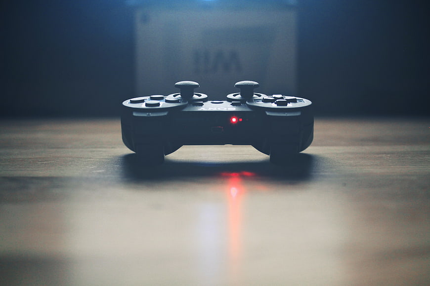 Dark moody gaming controller with red light on wooden table