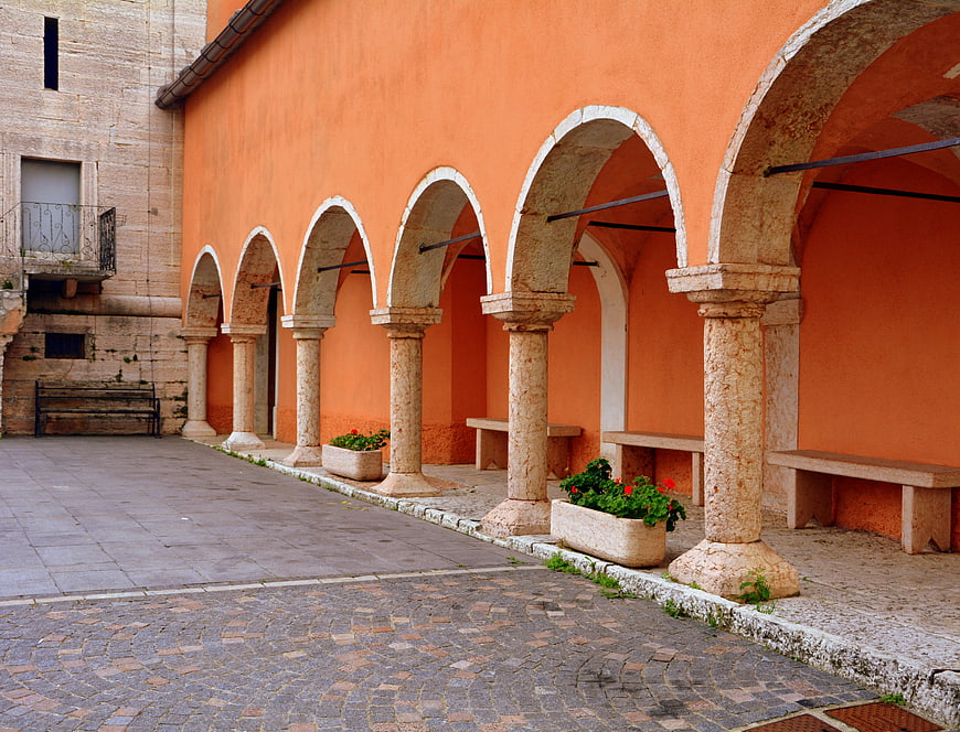 Orange arched colonnade in Italian courtyard with stone pillars