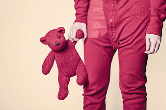 Person in red onesie holding red teddy bear