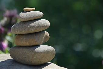 Stacked Zen Stones on Rock with Blurred Green Garden Background