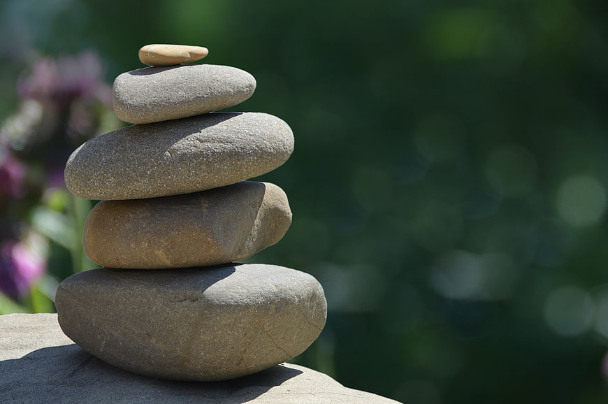 Stacked Zen Stones on Rock with Blurred Green Garden Background