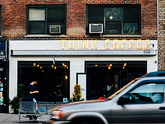 Urban street scene with Think Coffee shop and passing car