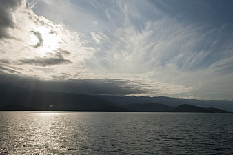 Dramatic Sun Rays Over Calm Sea and Mountains
