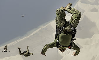 Military Paratroopers Freefalling Over Snowy Mountain Terrain
