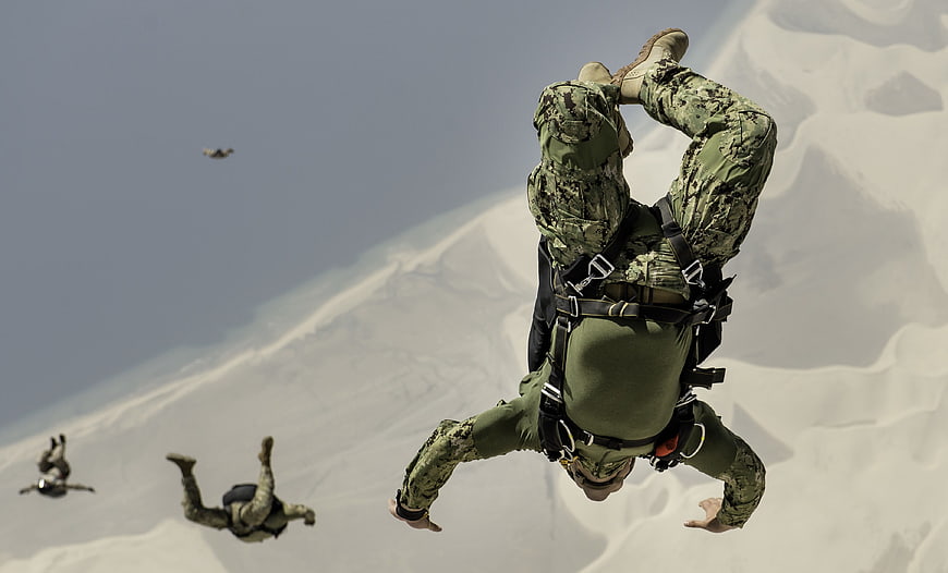 Military Paratroopers Freefalling Over Snowy Mountain Terrain