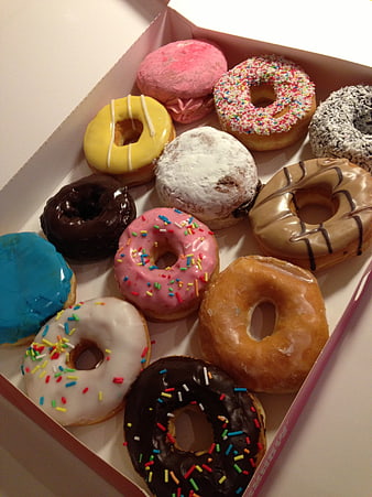 Assorted Glazed Donuts With Sprinkles In A Pink Box