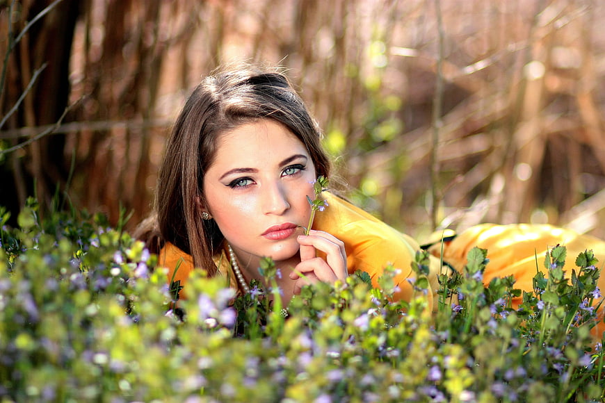 Brunette Woman in Yellow Dress Lying in Spring Flowers