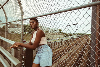 Stylish Black Woman Leaning on Urban Bridge Fence