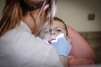 Dentist examining young boy's teeth in clinic chair