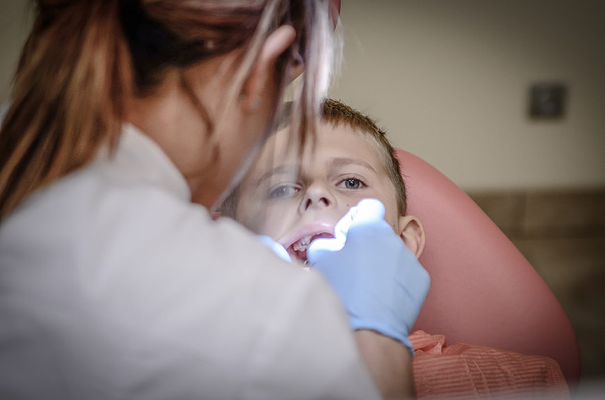 Dentist examining young boy's teeth in clinic chair